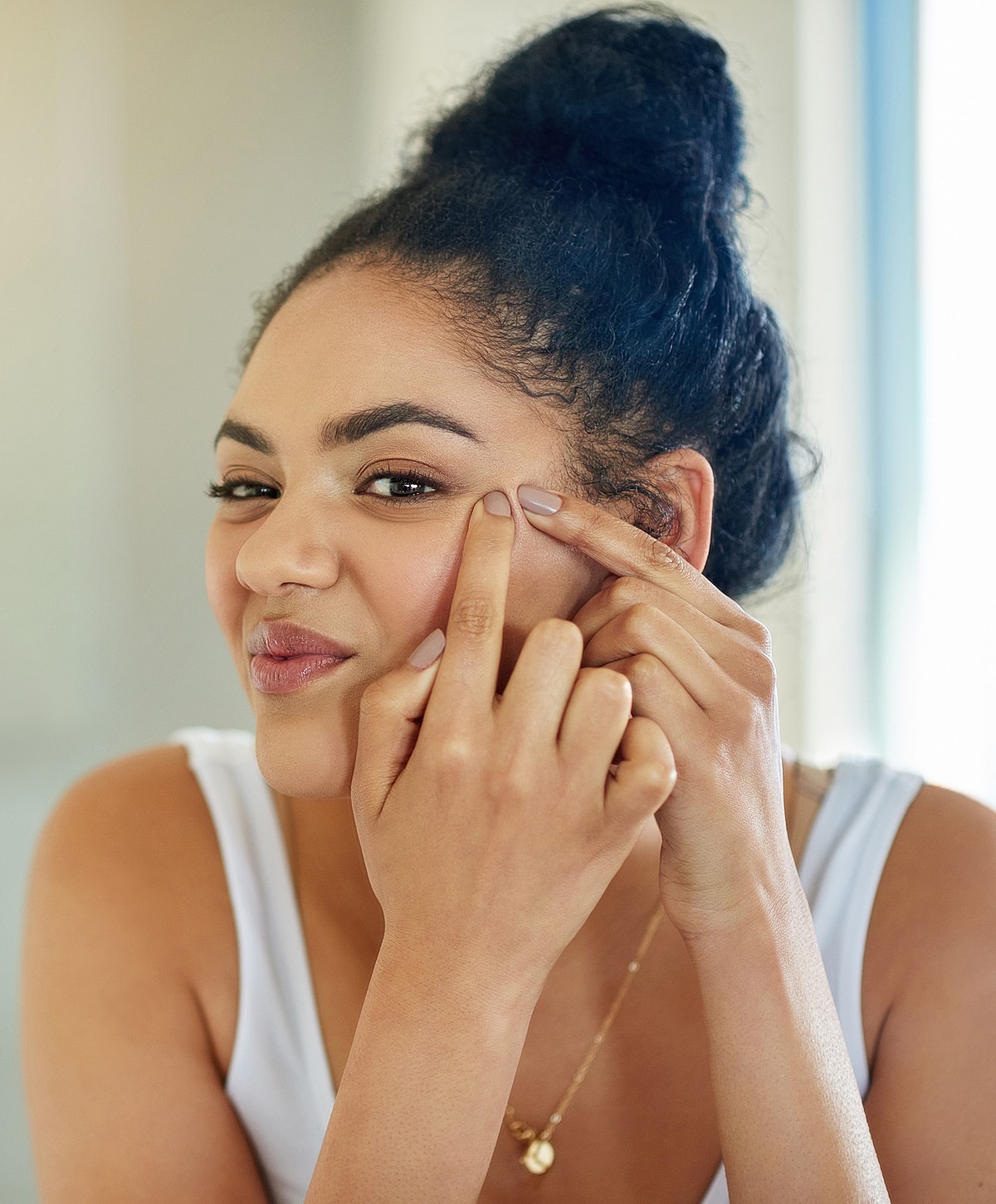 Woman demonstrating skincare routine on her face.