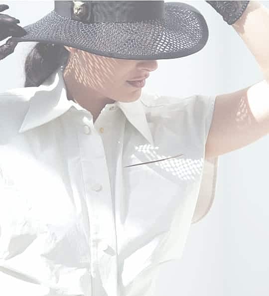 Woman in stylish hat and blouse, two-tone lighting.