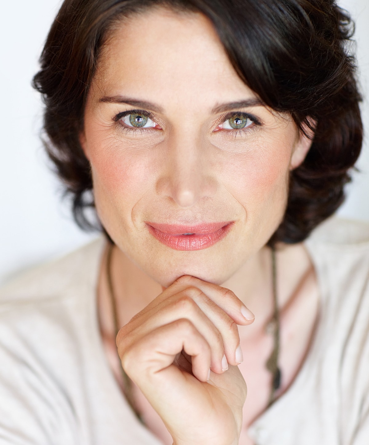 Smiling woman resting chin on hand.