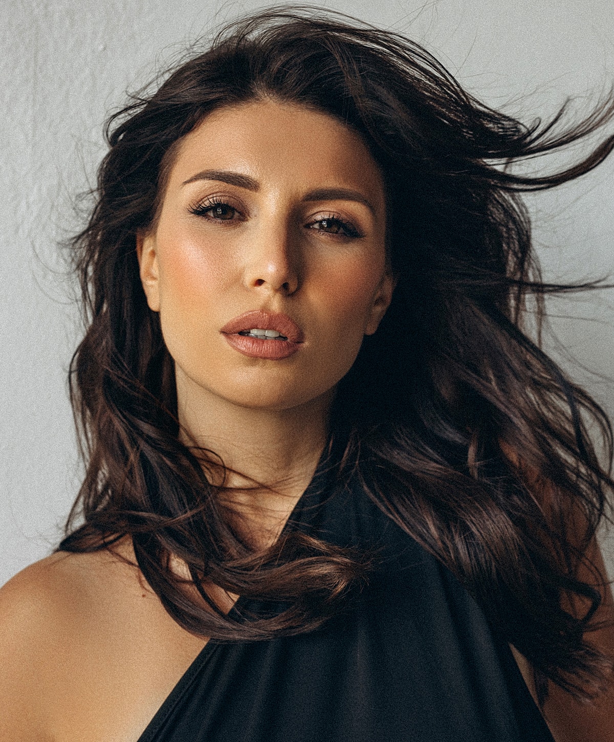 Woman with flowing hair against a neutral background.