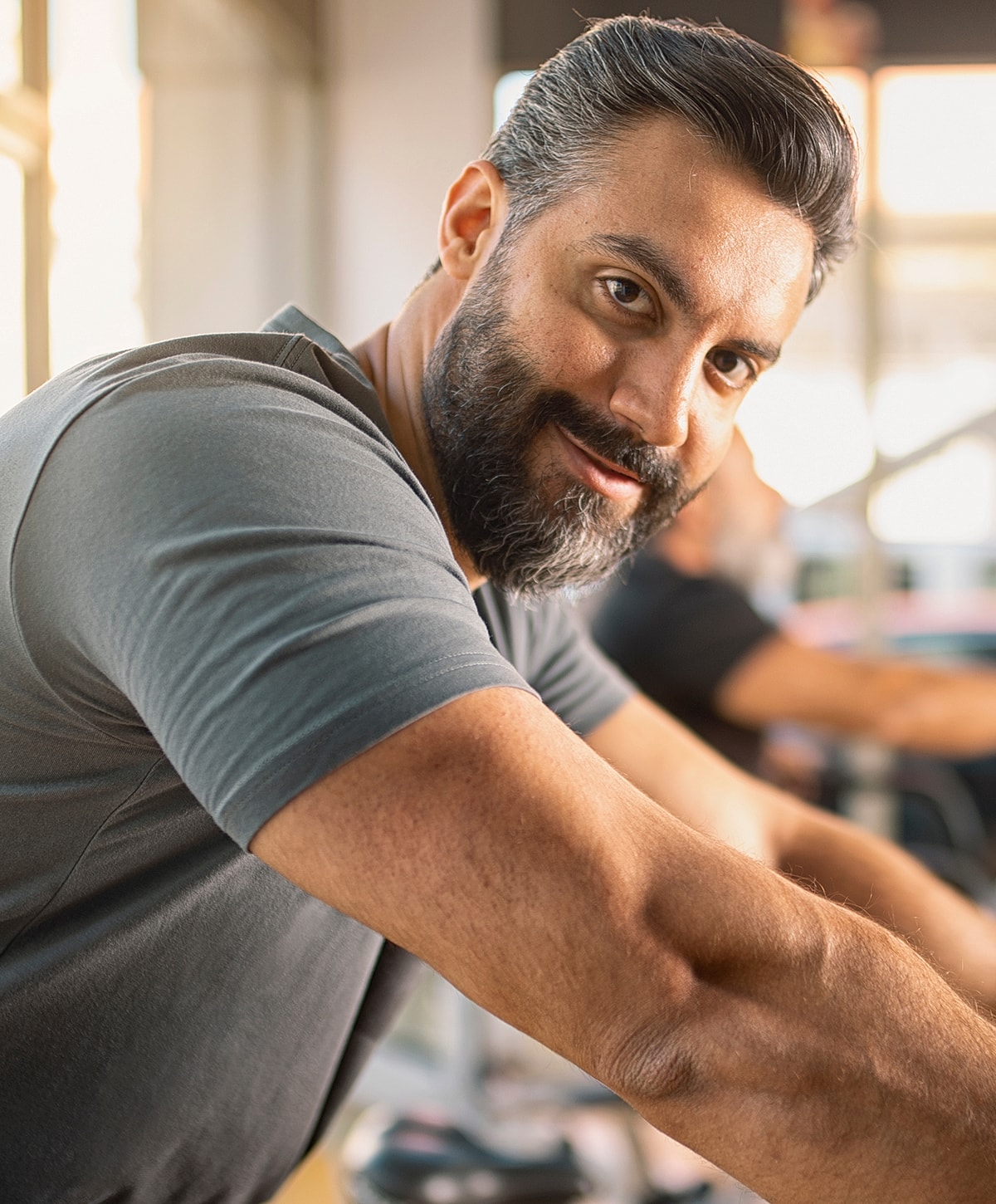 Man exercising in gym, looking at camera.