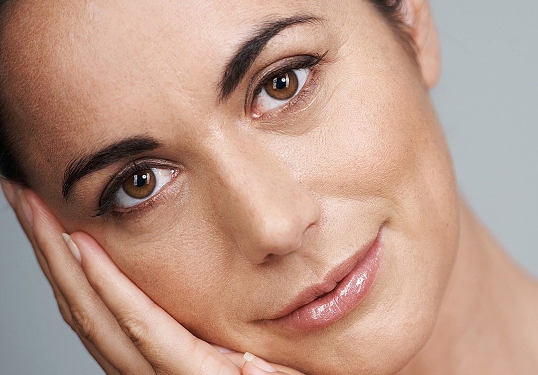 Woman resting her face on hands, smiling gently.
