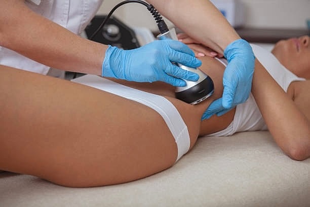 Woman receiving ultrasonic treatment on thigh.