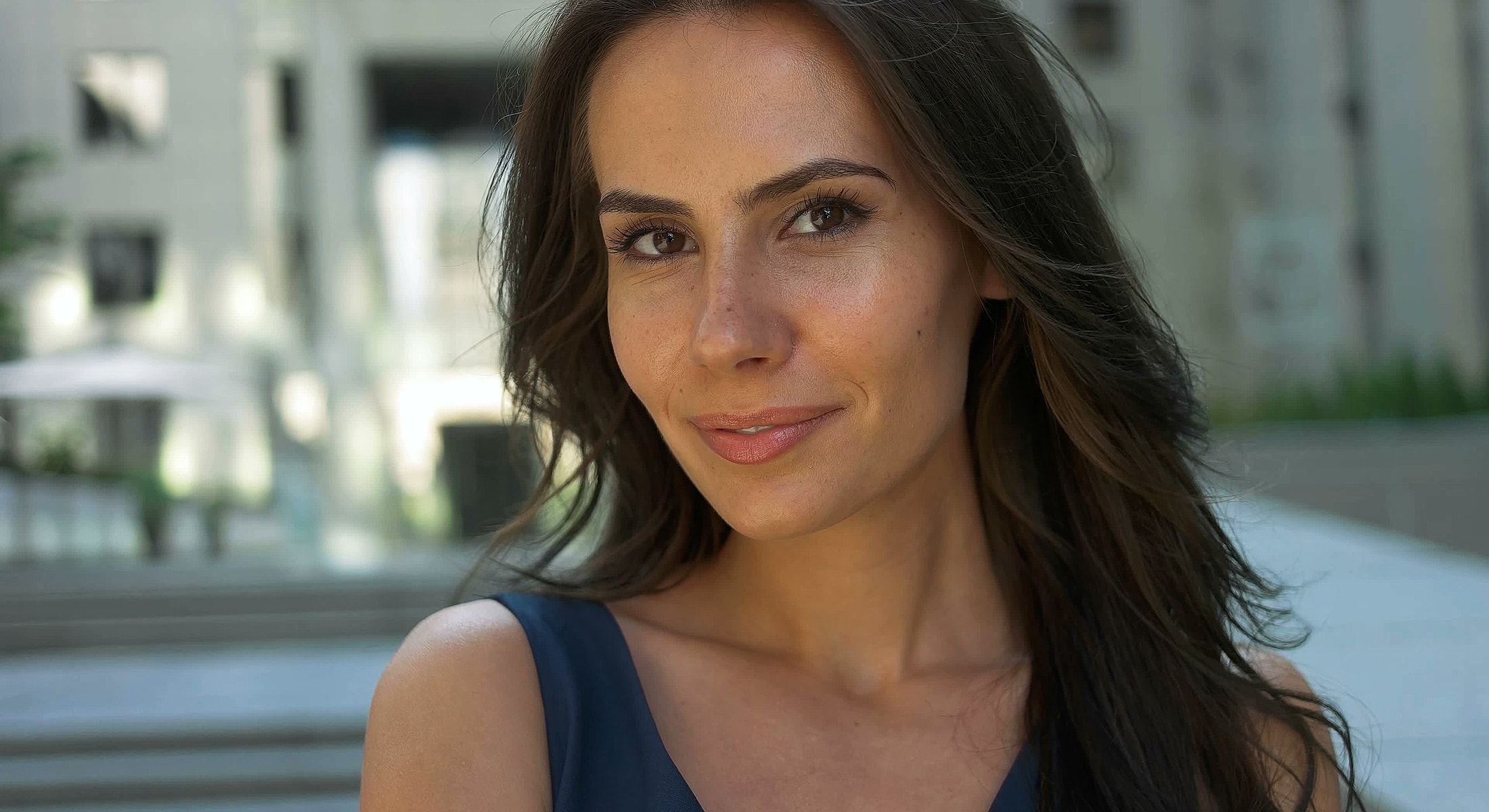 Smiling woman with long hair outdoors.