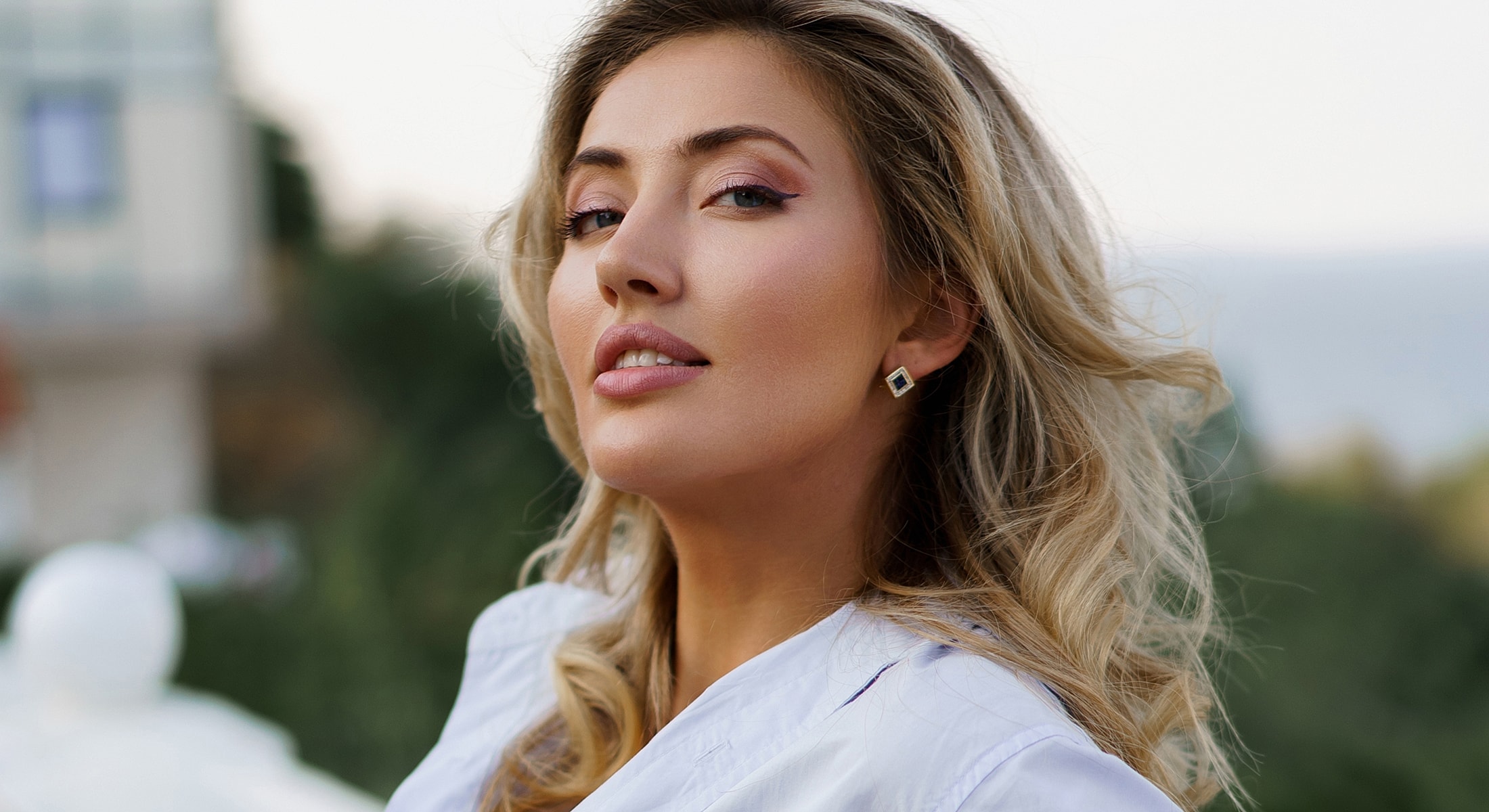Woman with blonde hair posing outdoors.