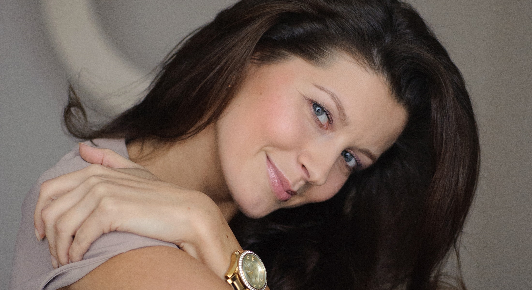 Smiling woman with long dark hair and watch.