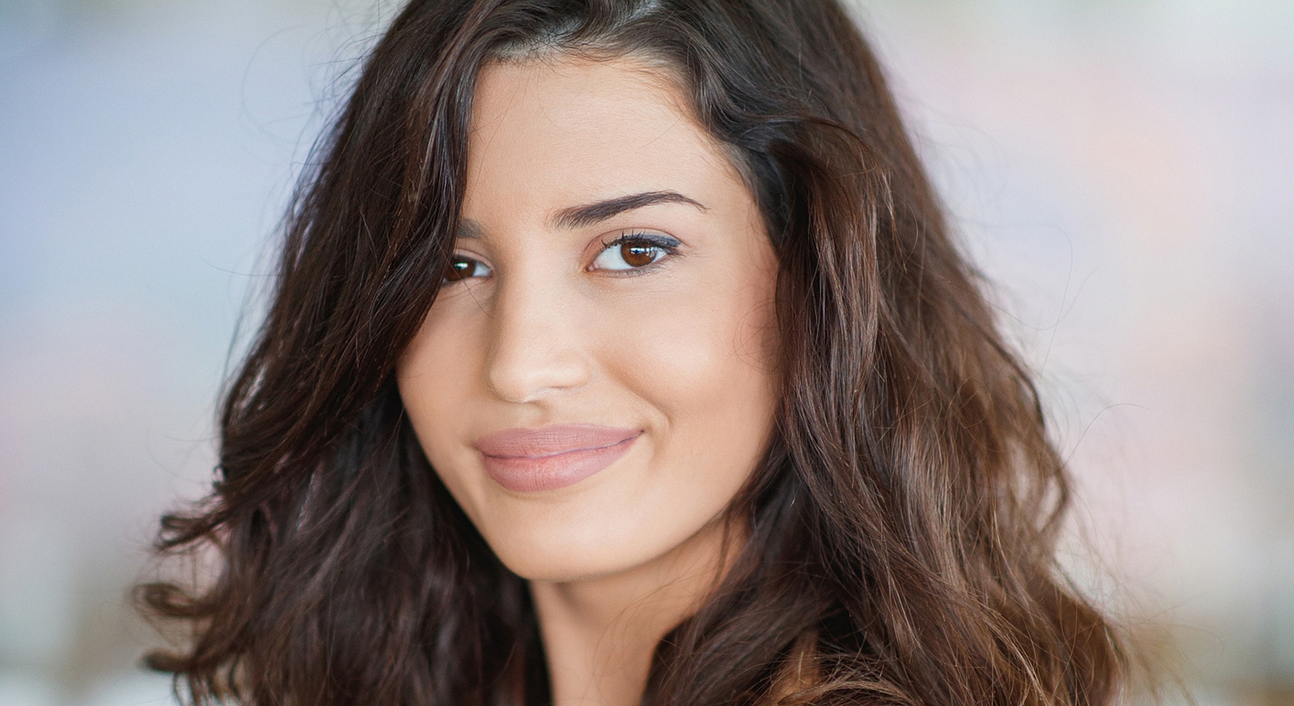 Smiling woman with long, wavy hair.