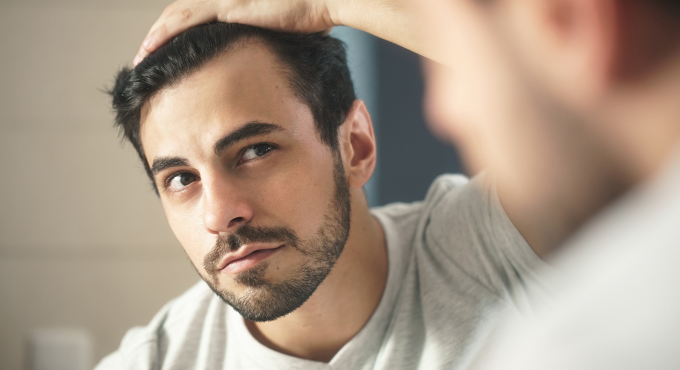 Man examining his hair in the mirror.