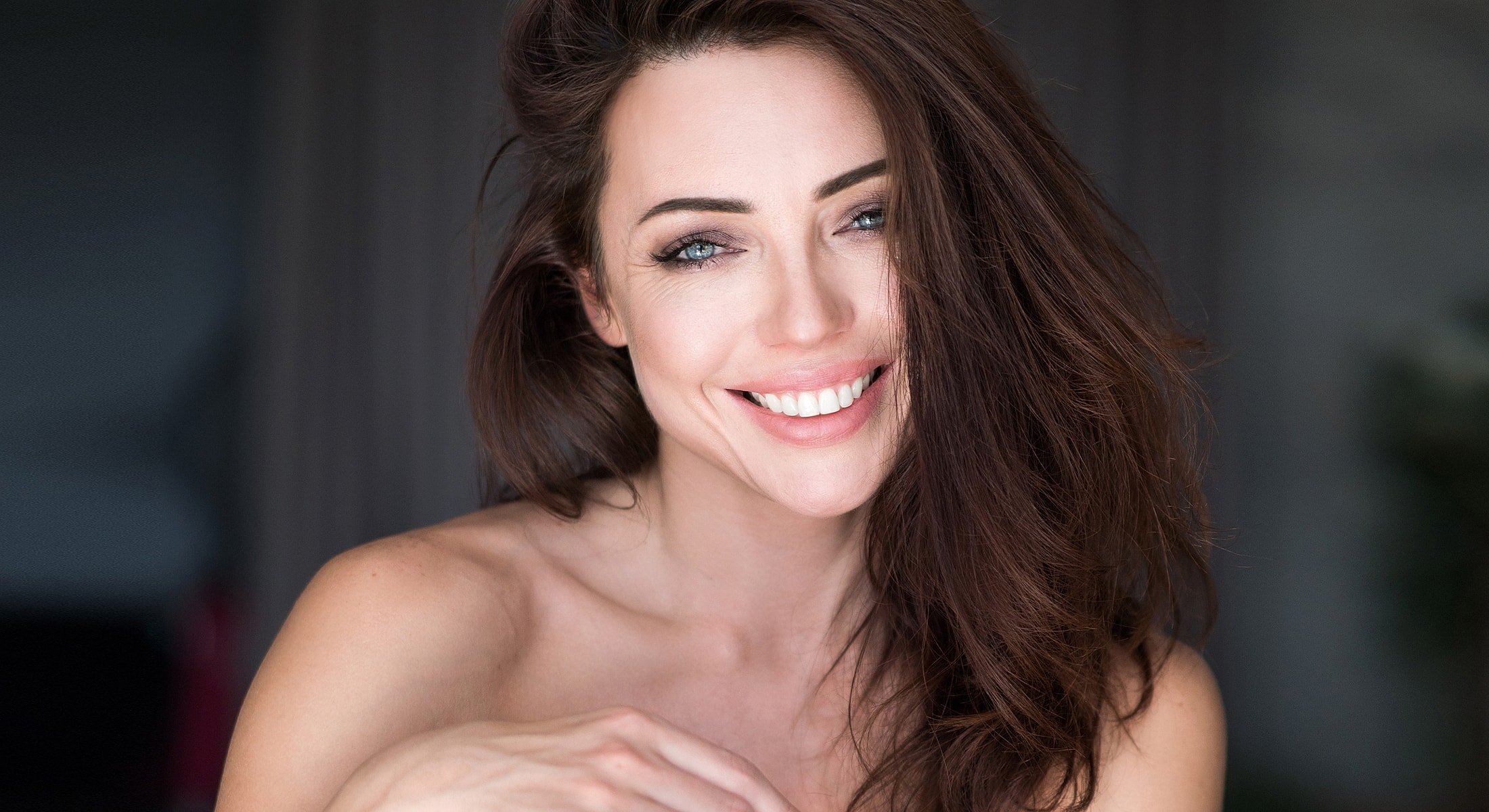 Smiling woman with long, dark hair indoors.